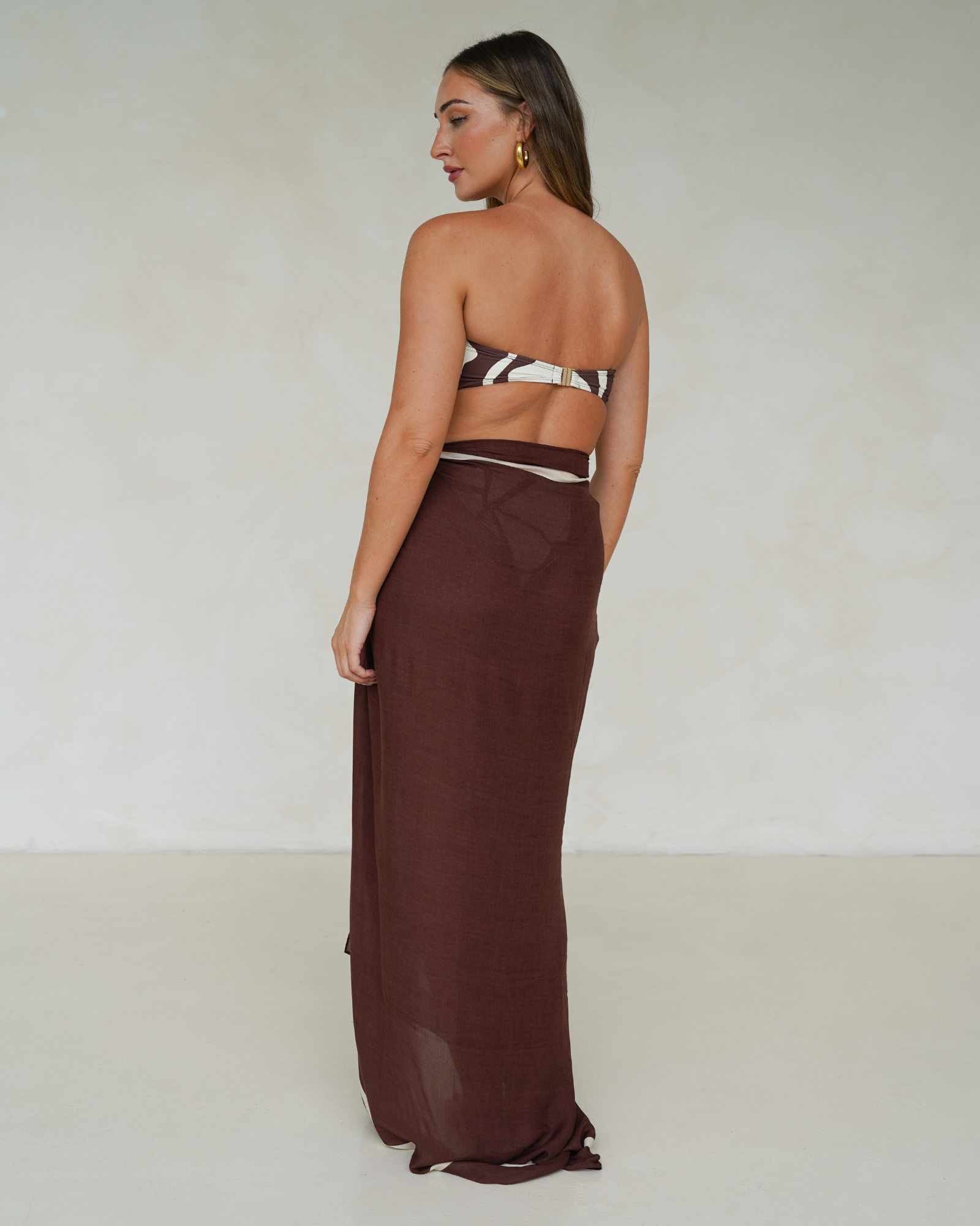 Model wearing chocolate brown rayon sarong with cream trim, styled over matching printed bandeau bikini – Ochre Lane resortwear