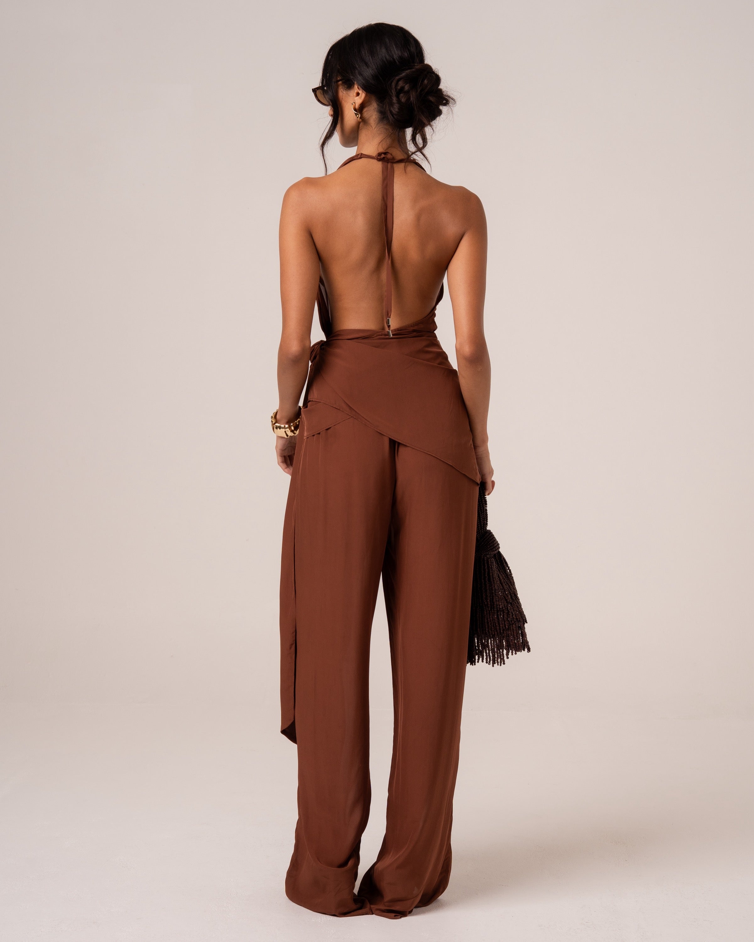Back view of a chocolate brown halter wrap top showing the deep open back and halter tie