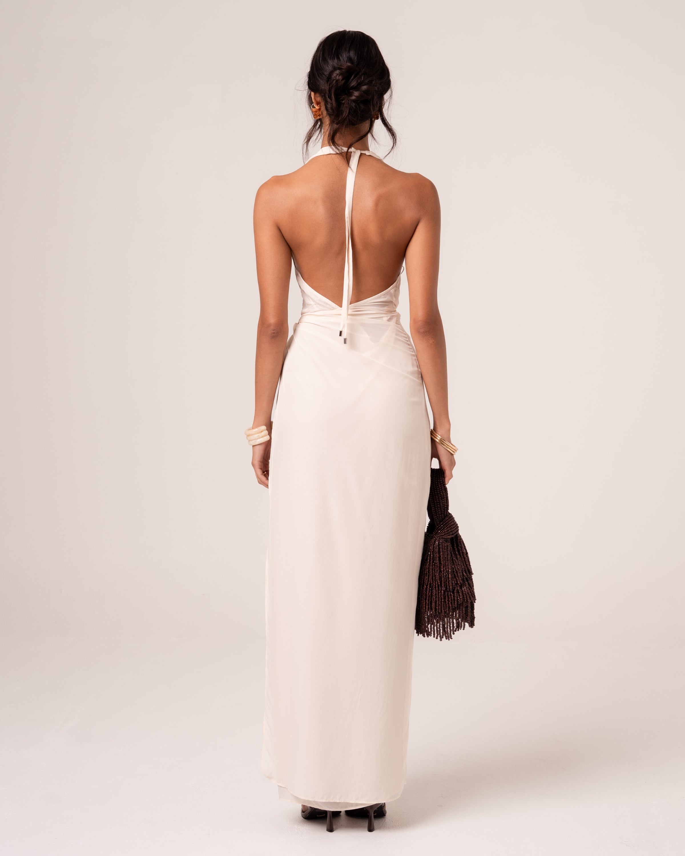 Back view of an ivory halter maxi dress showing the deep open back and beaded halter tie ends