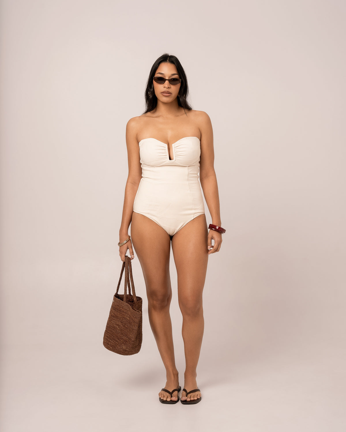 Model wearing an ivory strapless bandeau one piece swimsuit with a V-wire plunge neckline, studio front view
