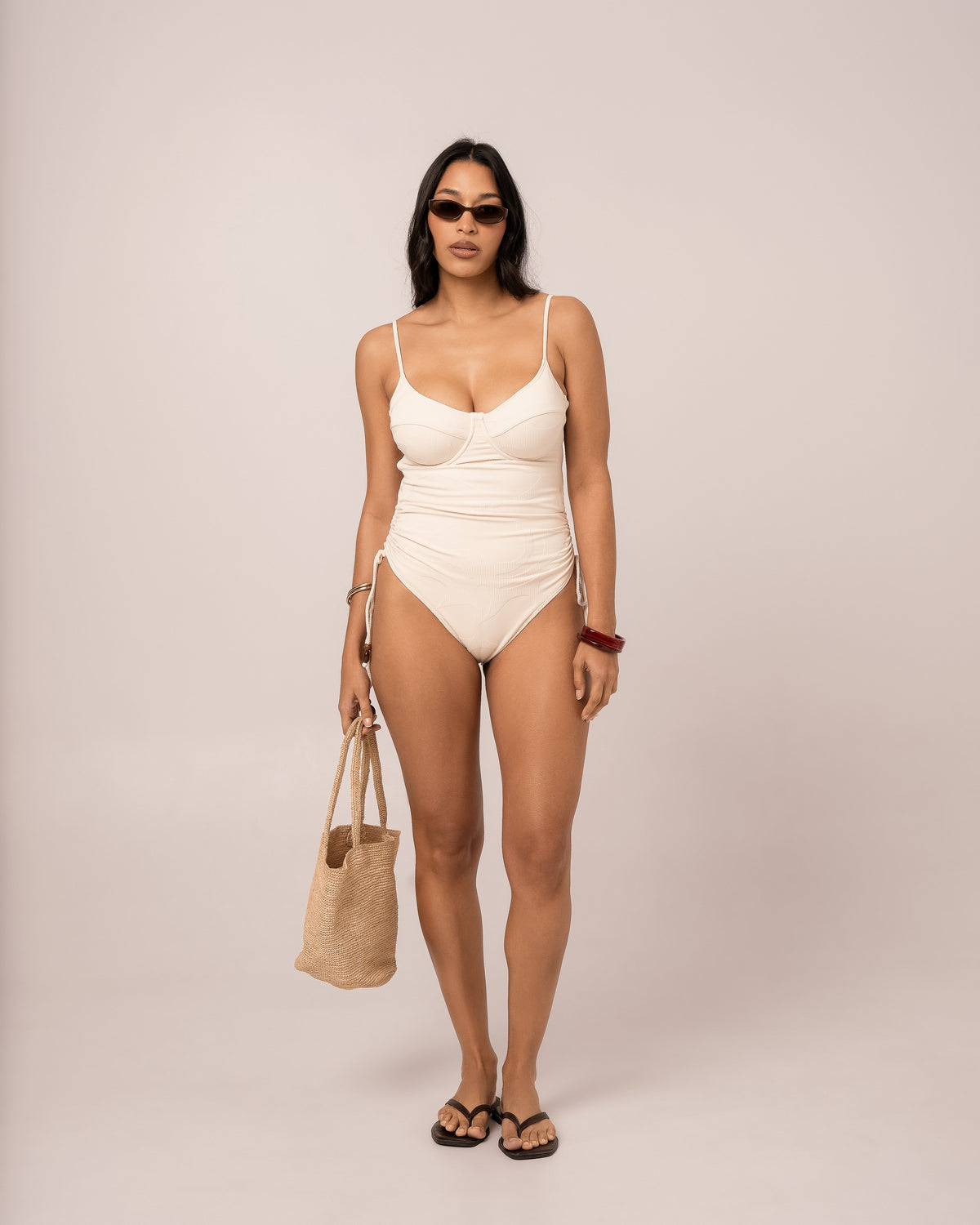 Model wearing an ivory thin strap underwire one piece swimsuit with structured cups, studio front view