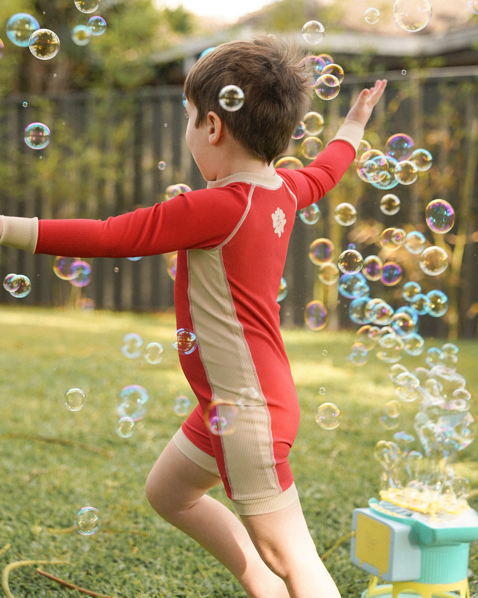 Child wearing Ochre Lane kids melon surfsuit with cream contrast panels on grass