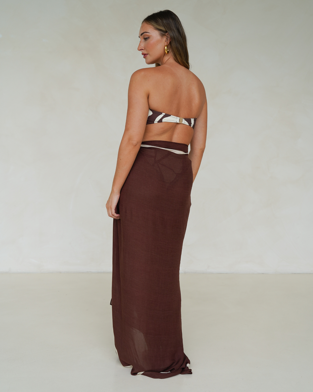 Model wearing chocolate brown rayon sarong with cream trim, styled over matching printed bandeau bikini – Ochre Lane resortwear