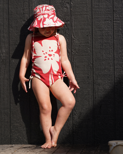Girl wearing Ochre Lane Solana print kids scoop one piece in red floral at the beach