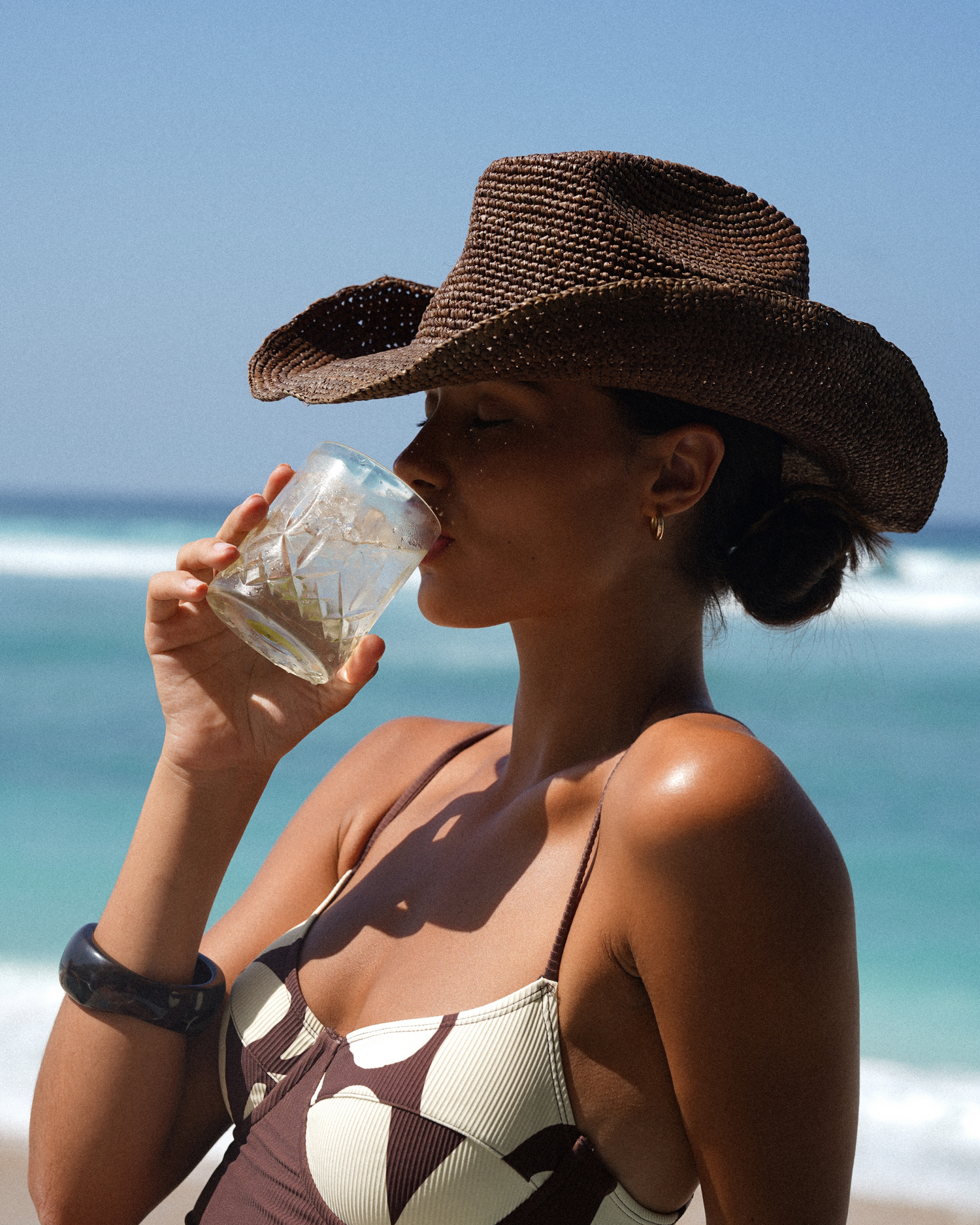 Handwoven raffia straw cowboy hat in Cocoa dark brown with wide brim and adjustable inner band.