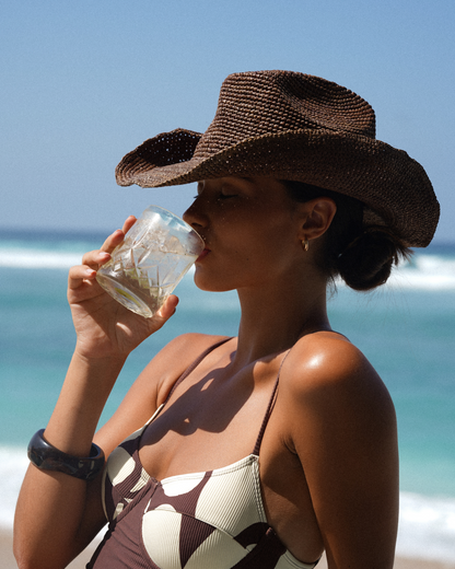 Handwoven raffia straw cowboy hat in Cocoa dark brown with wide brim and adjustable inner band.