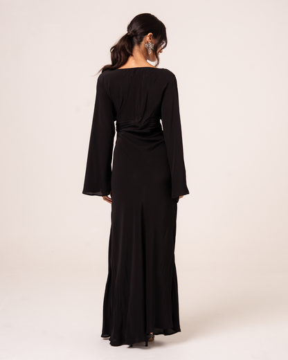 Back view of black batwing maxi dress with wide sleeves and draped silhouette, studio