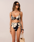 Model wearing a black and cream botanica floral print high waist tie side bikini bottom with ruched side detail and matching underwire top, studio front view