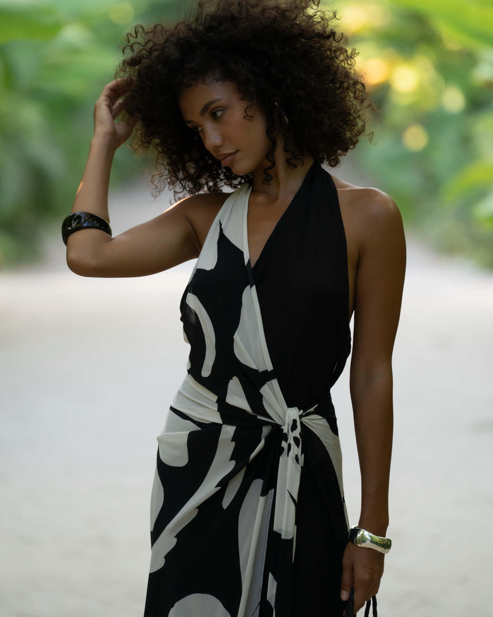 Close-up of a model wearing a black and cream floral halter wrap maxi dress showing the plunging neckline and tie detail