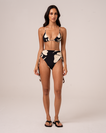 Woman wearing black and cream floral print high waist tie side bikini bottom and matching triangle top, front view