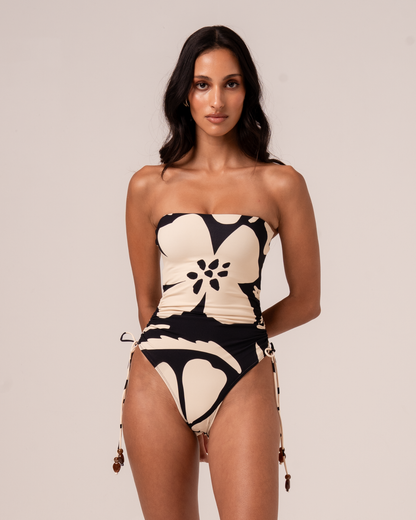 Botanica floral print strapless one-piece swimsuit in cream and black with ruched side tie, front close-up studio shot