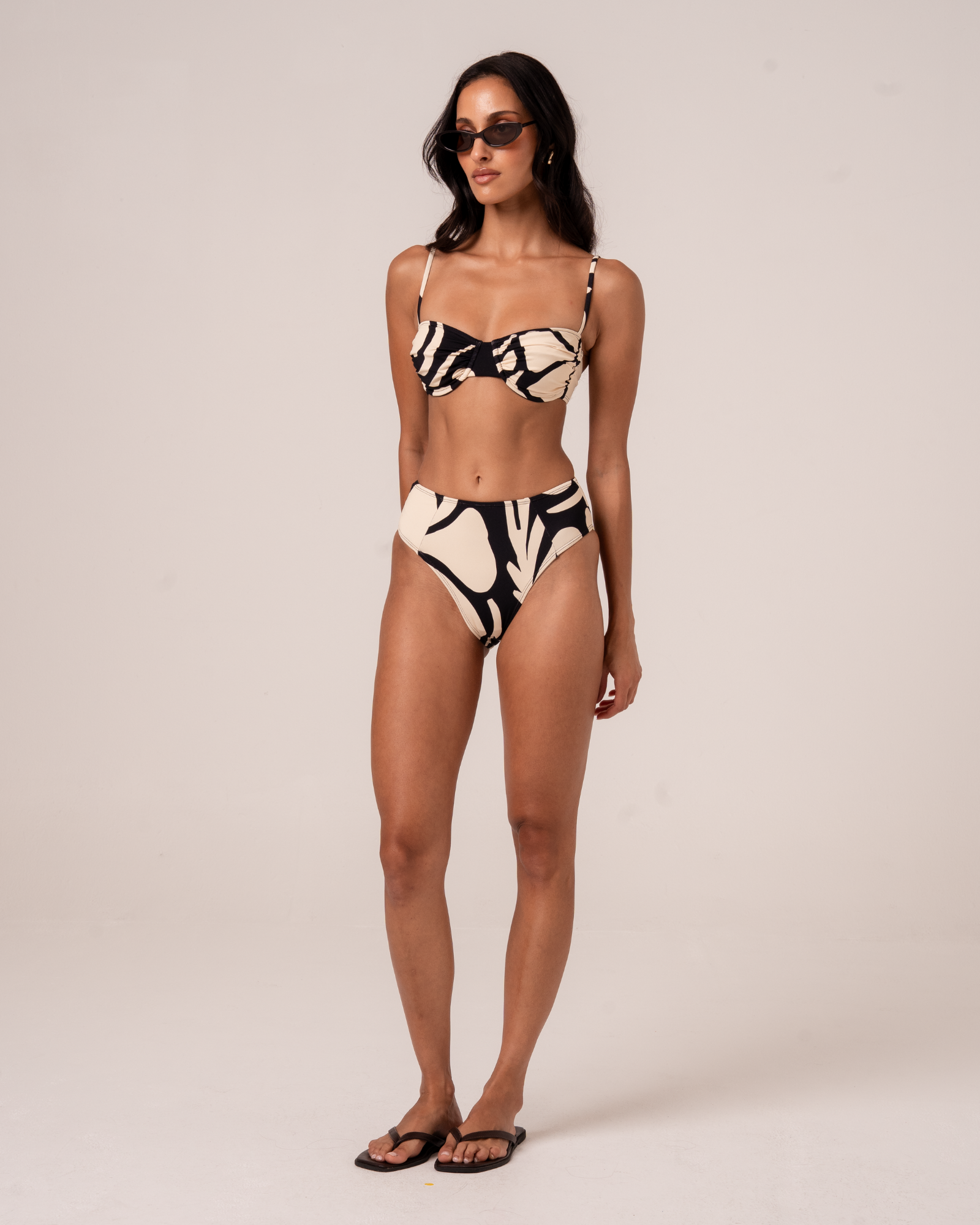 Botanica print ruched bandeau bralette in black and cream with high-waist bikini bottom, full-length studio shot