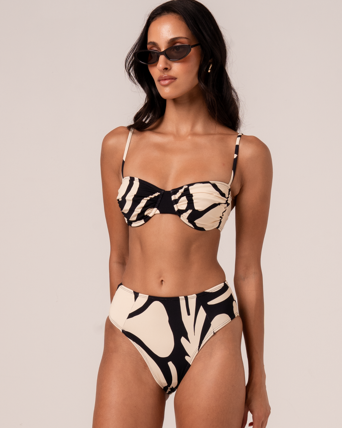 Botanica print mid-rise bikini bottom in black and cream, styled with a ruched bandeau top, front view studio shot