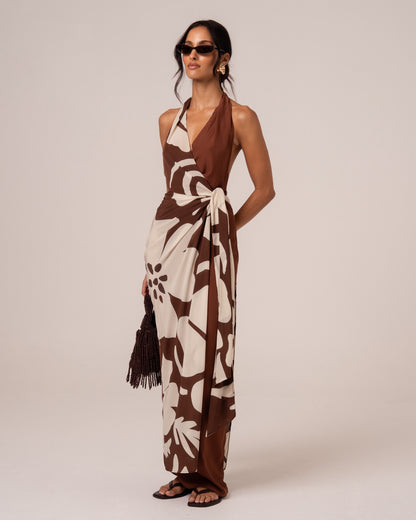 Side view of a brown and cream floral halter wrap maxi dress with a cascading waist tie drape, studio setting