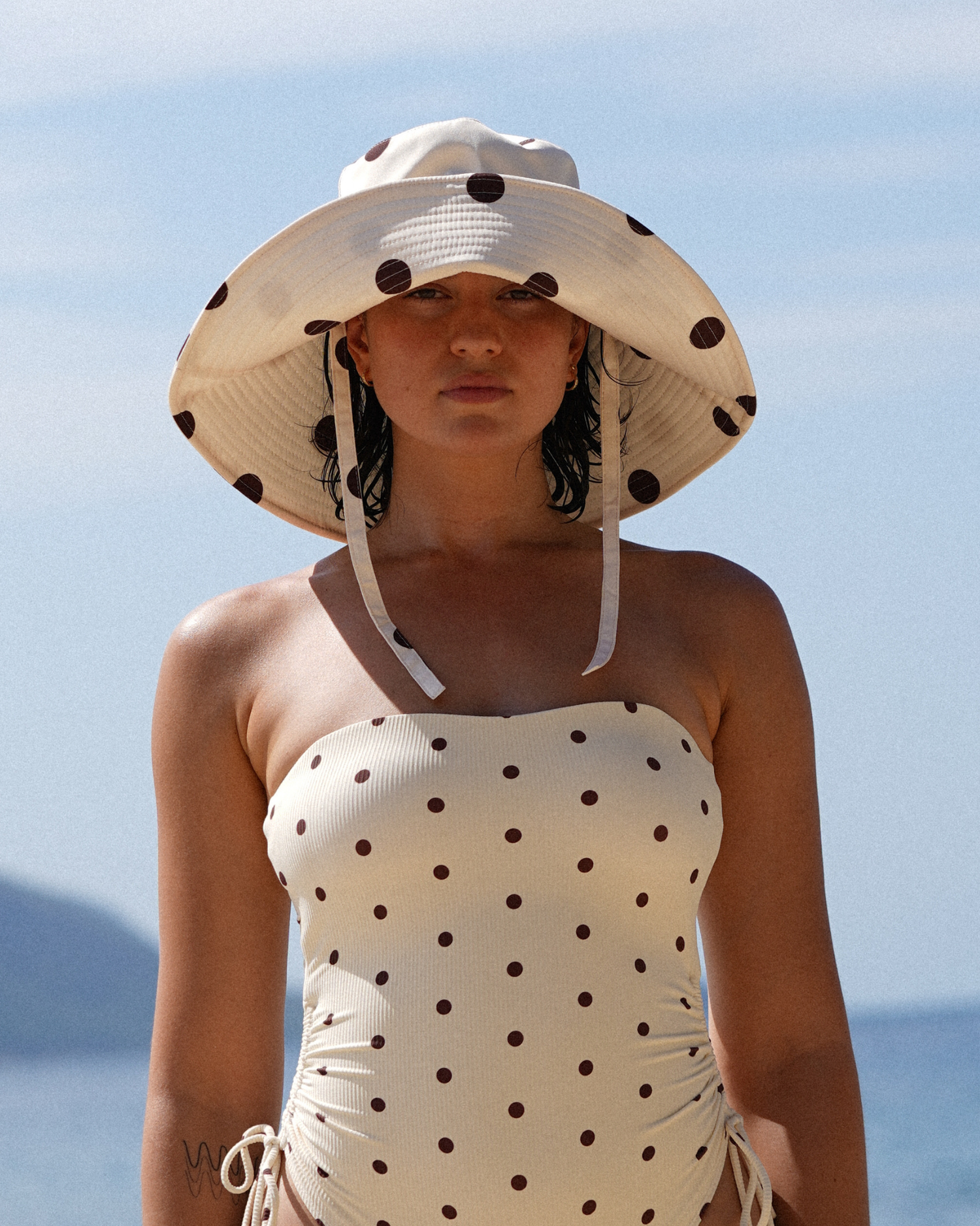 Ochre Lane Sun Hat in butter yellow polkadot print, wide brim bucket design for beach and resort styling.