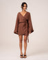 Model wearing a chocolate brown batwing wrap mini dress with a deep V-neckline and wide sleeves, studio front view