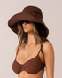 Model wearing a chocolate brown wide-brim cotton sun hat, three-quarter view with sunglasses and bikini
