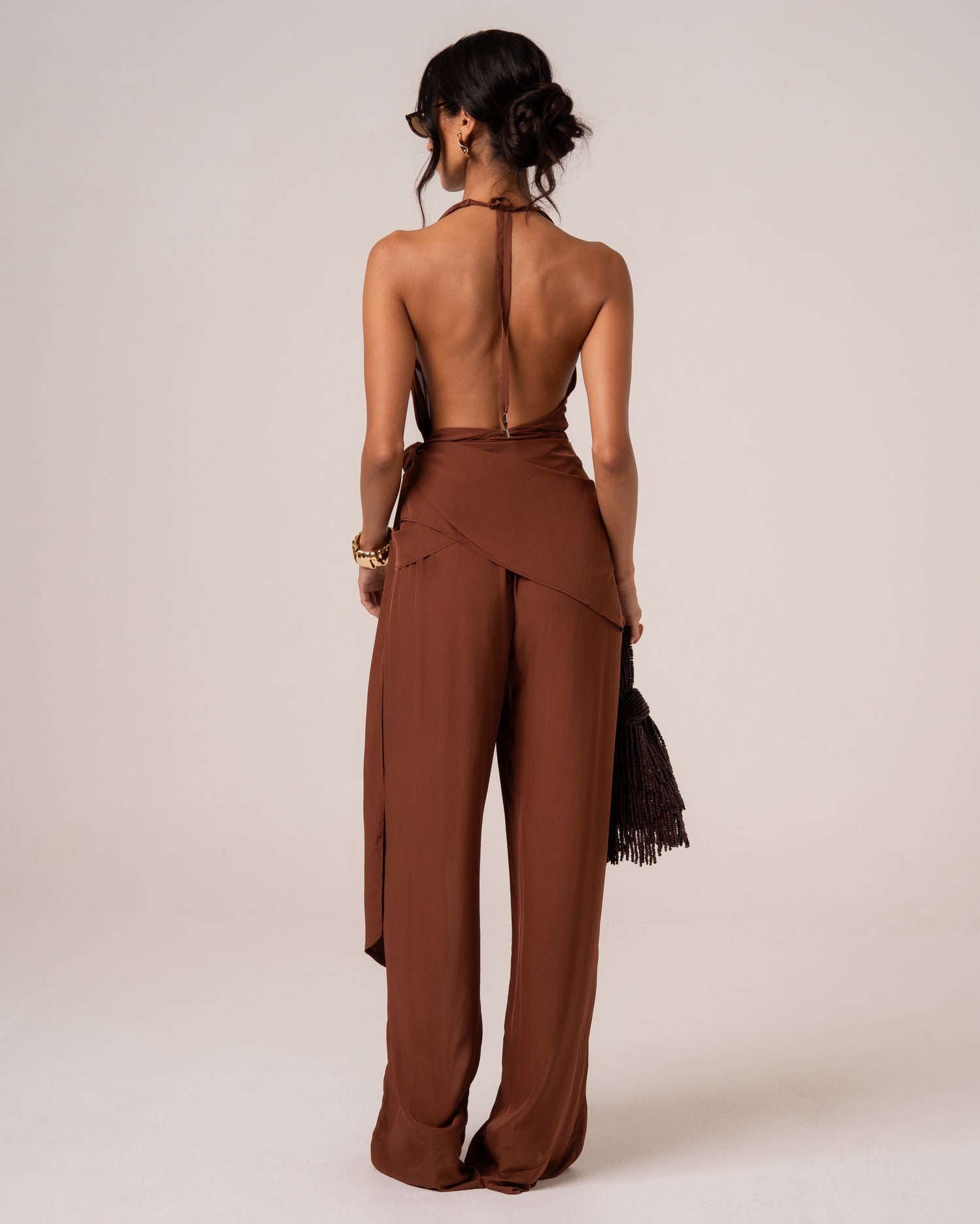 Back view of a chocolate brown halter wrap top showing the deep open back and halter tie
