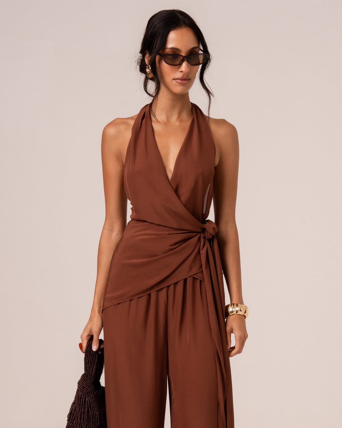 Front view of a chocolate brown halter wrap top with a draped side tie, studio setting