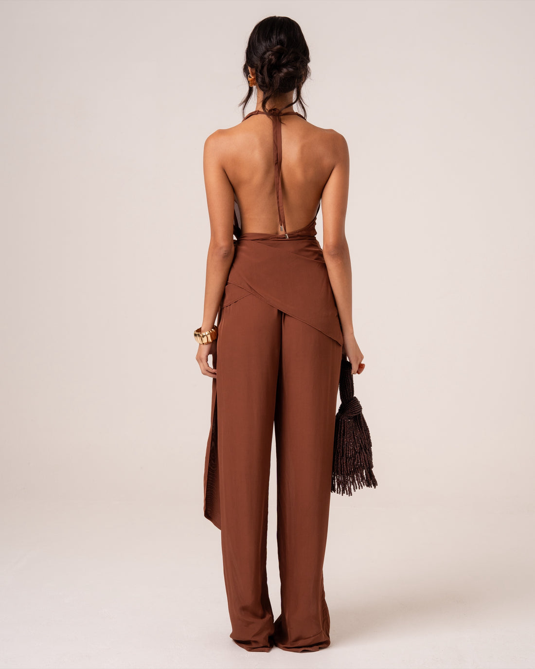 Back view of chocolate brown wide-leg resort pants with a draped waist tie, showing the full-length silhouette