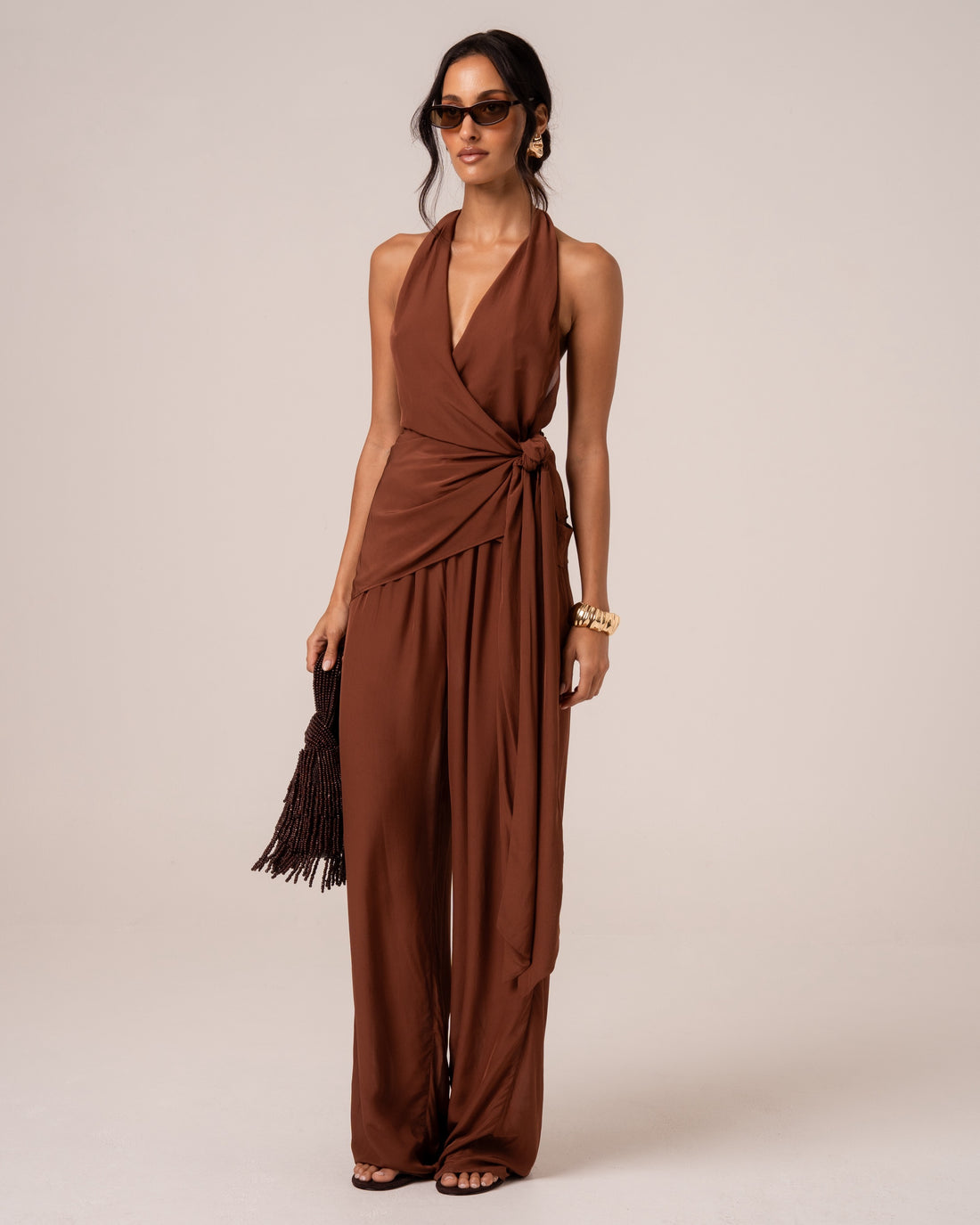Full-length front view of chocolate brown wide-leg resort pants, styled with a beaded bag