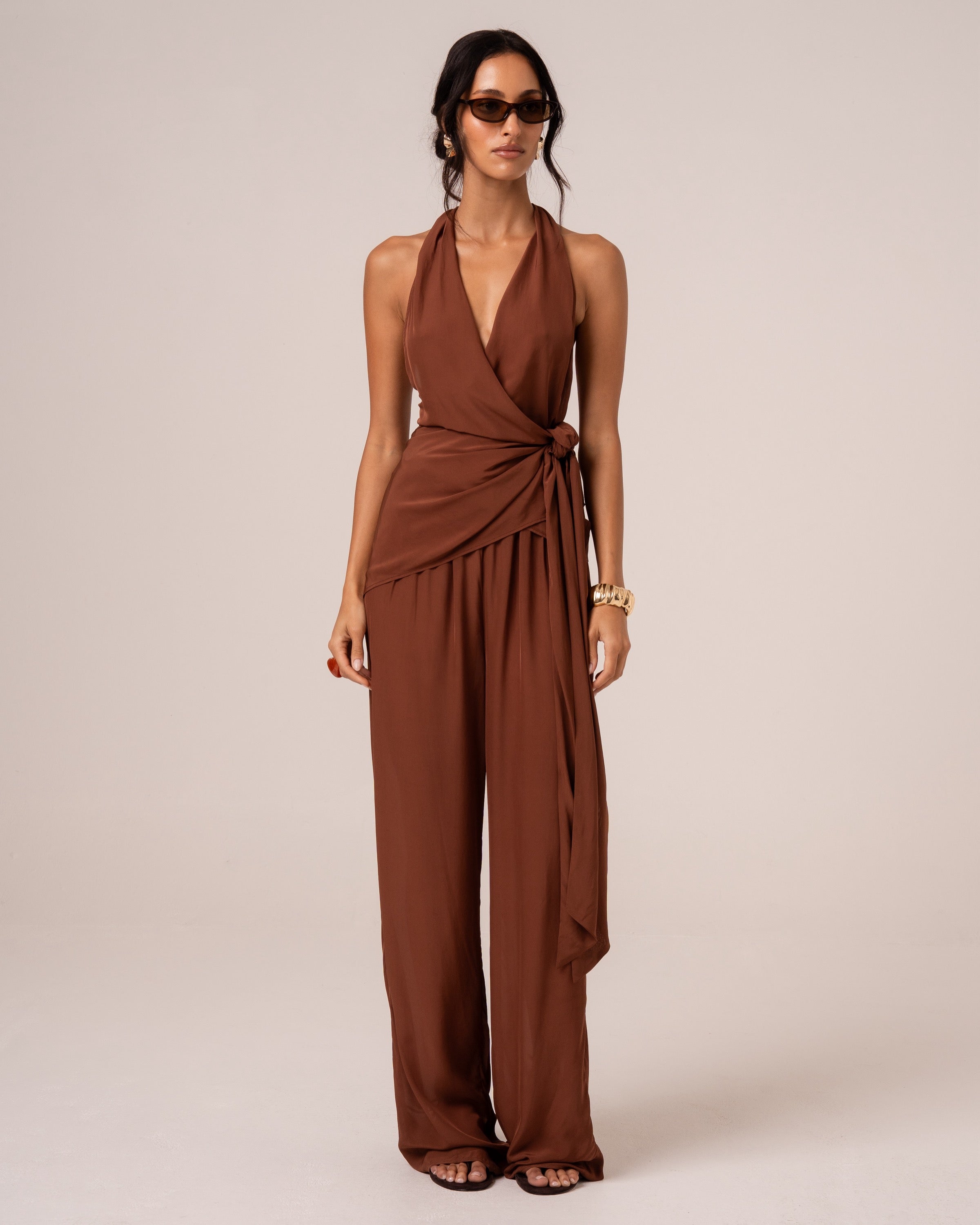 Front view of chocolate brown wide-leg resort pants with an elasticated drawstring waist, studio setting