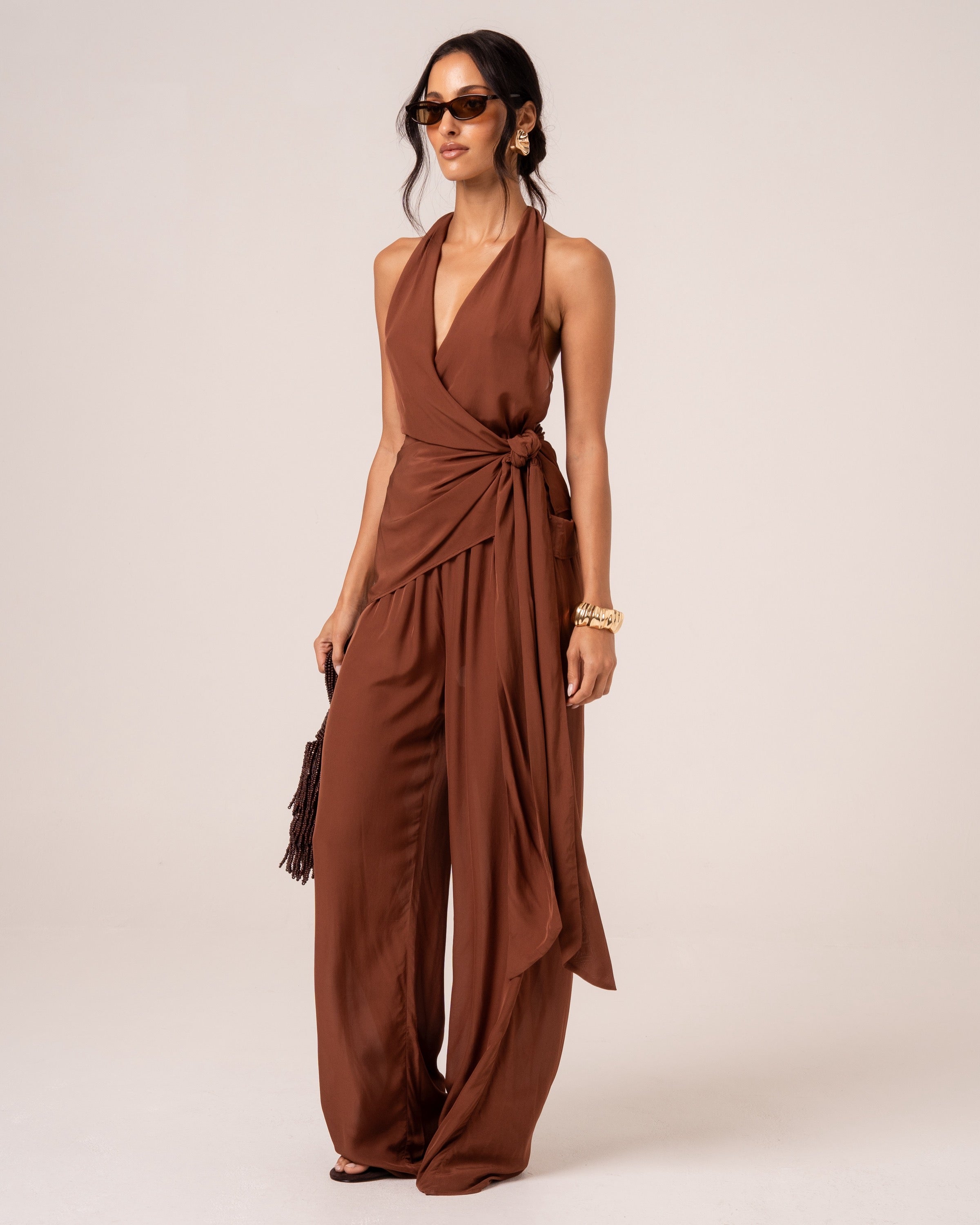 Model wearing chocolate brown wide-leg resort pants with an elasticated drawstring waist, styled with a matching wrap top, studio front view
