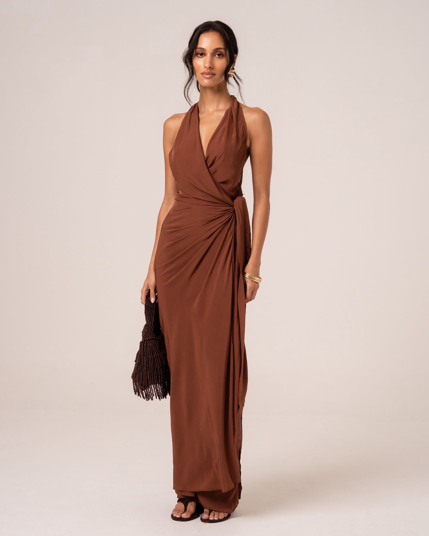 Front view of a chocolate brown wrap maxi dress with a plunging halter neckline, studio setting