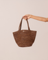 Cocoa brown woven raffia mini tote held by the handle, front product view on a plain neutral background