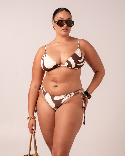 Model wearing a brown and cream Ibisco floral print bikini set with a triangle top and tie-side bottom, studio front view