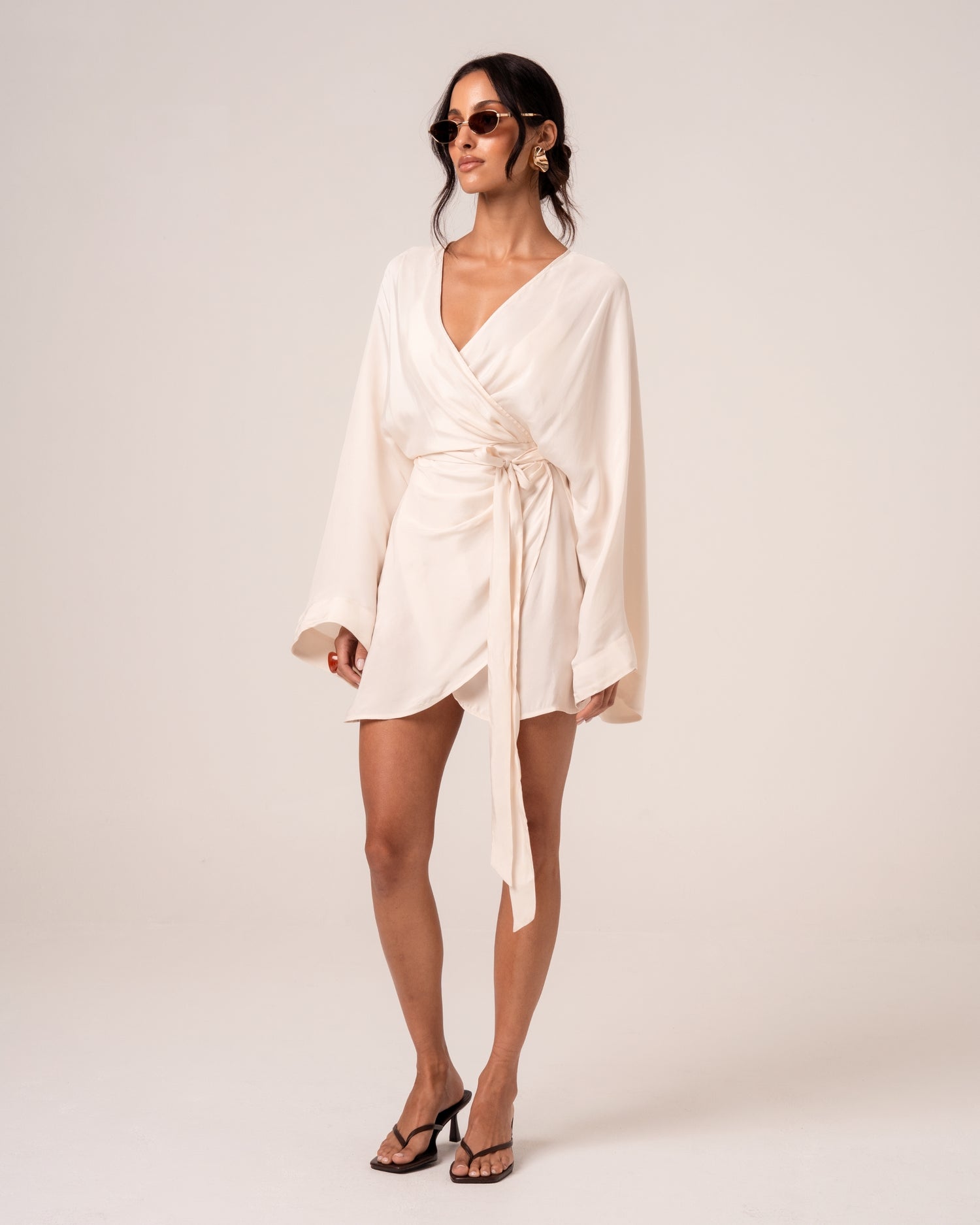 Ivory wrap mini dress with wide batwing sleeves and an asymmetric hem, three-quarter view