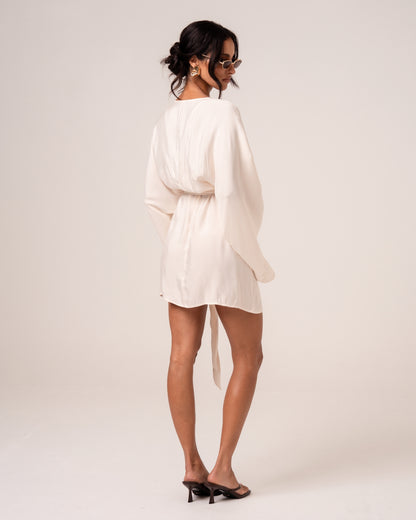 Back view of an ivory batwing wrap mini dress showing the clean back and wide sleeves