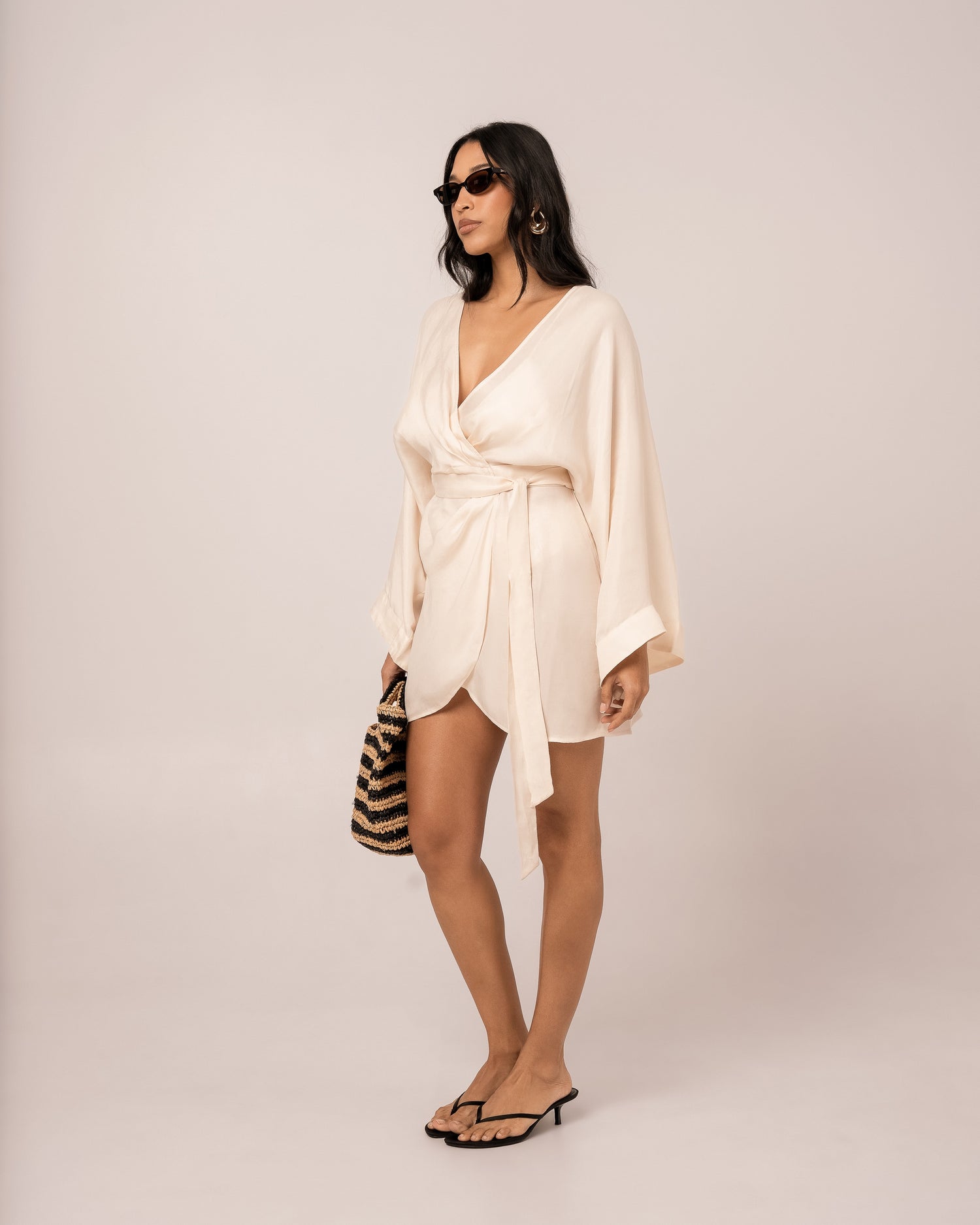 Ivory batwing wrap mini dress showing the wide fluid batwing sleeve draping to the wrist