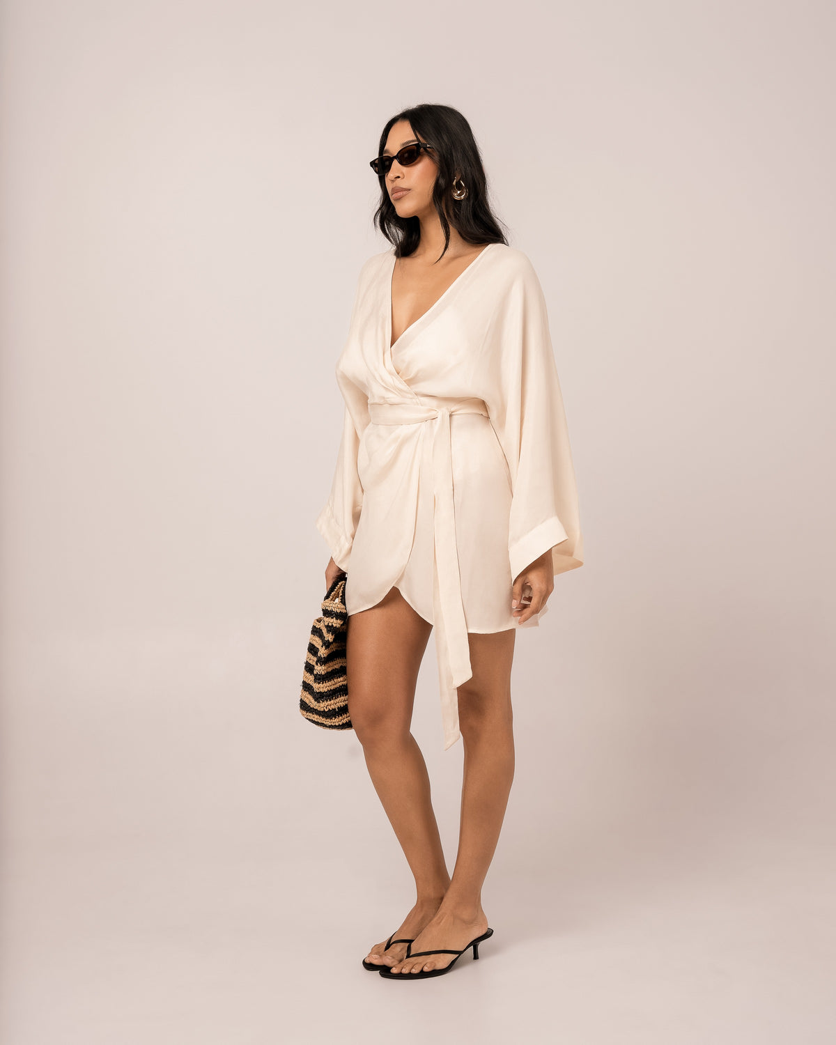 Ivory batwing wrap mini dress showing the wide fluid batwing sleeve draping to the wrist