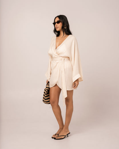 Ivory batwing wrap mini dress showing the wide fluid batwing sleeve draping to the wrist