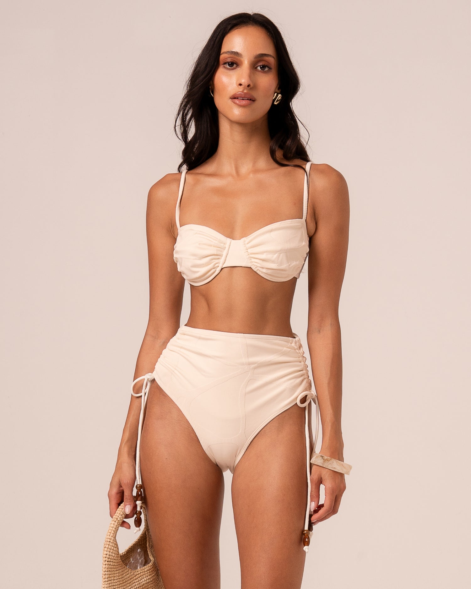 Ivory high waist bikini bottom with ruched sides and beaded adjustable side ties, styled with a bandeau top — studio front view