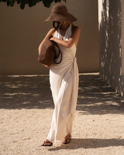 Ivory wrap maxi dress styled with a chocolate raffia sun hat and woven raffia tote — elevated honeymoon resortwear
