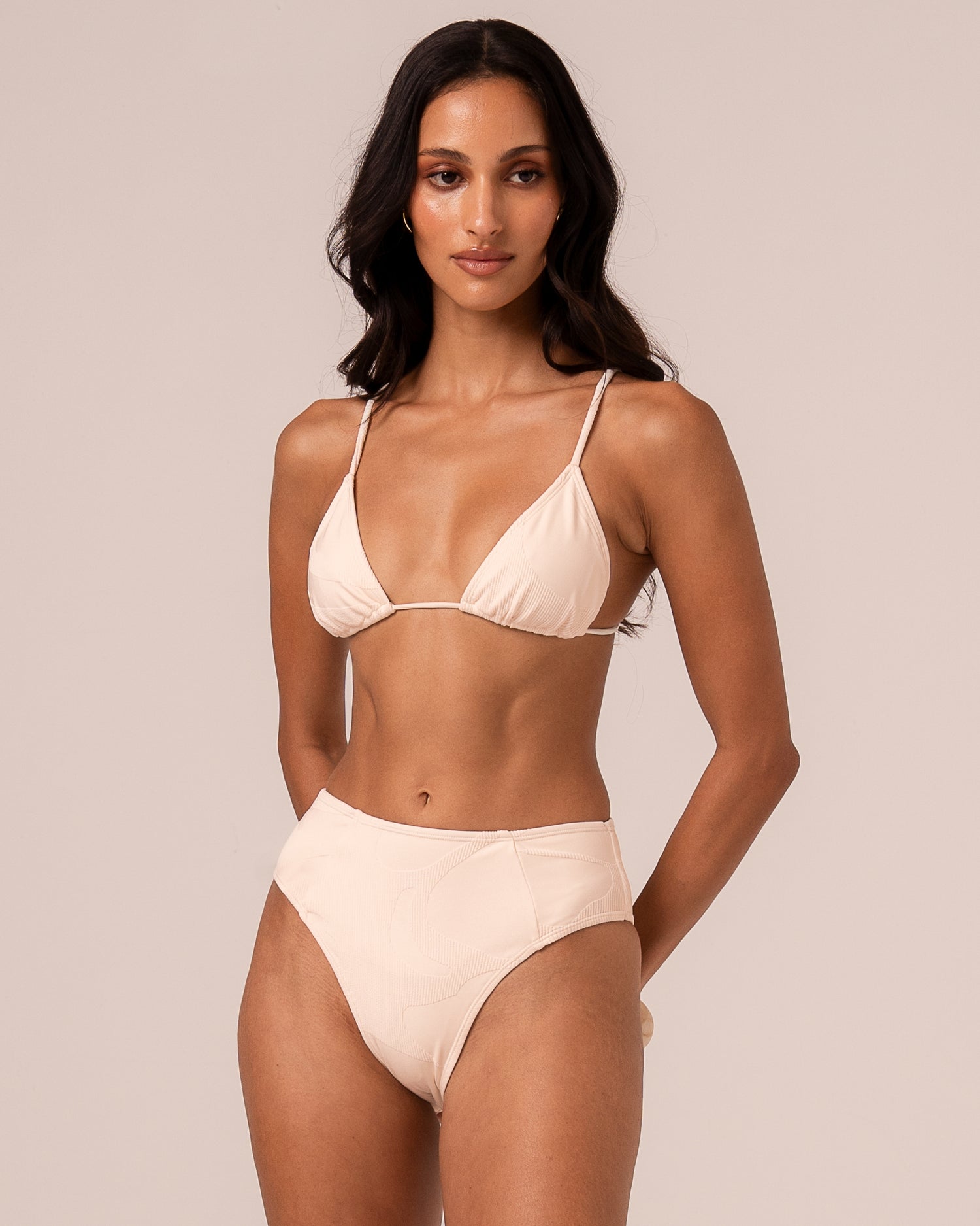 Ivory mid rise bikini bottom showing the elongating spliced panel seams and higher-cut leg, three-quarter front view