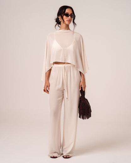 Front view of ivory viscose palazzo-style beach pants showing the gold-tipped drawstring waist, styled with a matching sheer cape