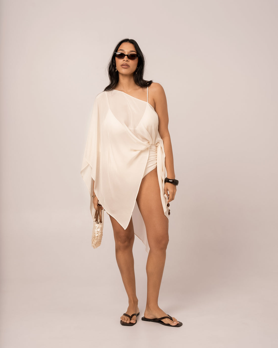 Ivory resort cape with fluid batwing sleeves and an angled draped hem, layered for honeymoon evenings