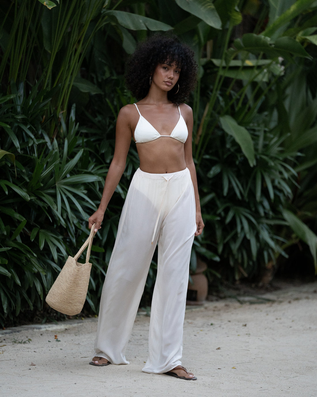 Ivory viscose drawstring beach pants styled with a white triangle bikini top and straw bag — honeymoon resort wear