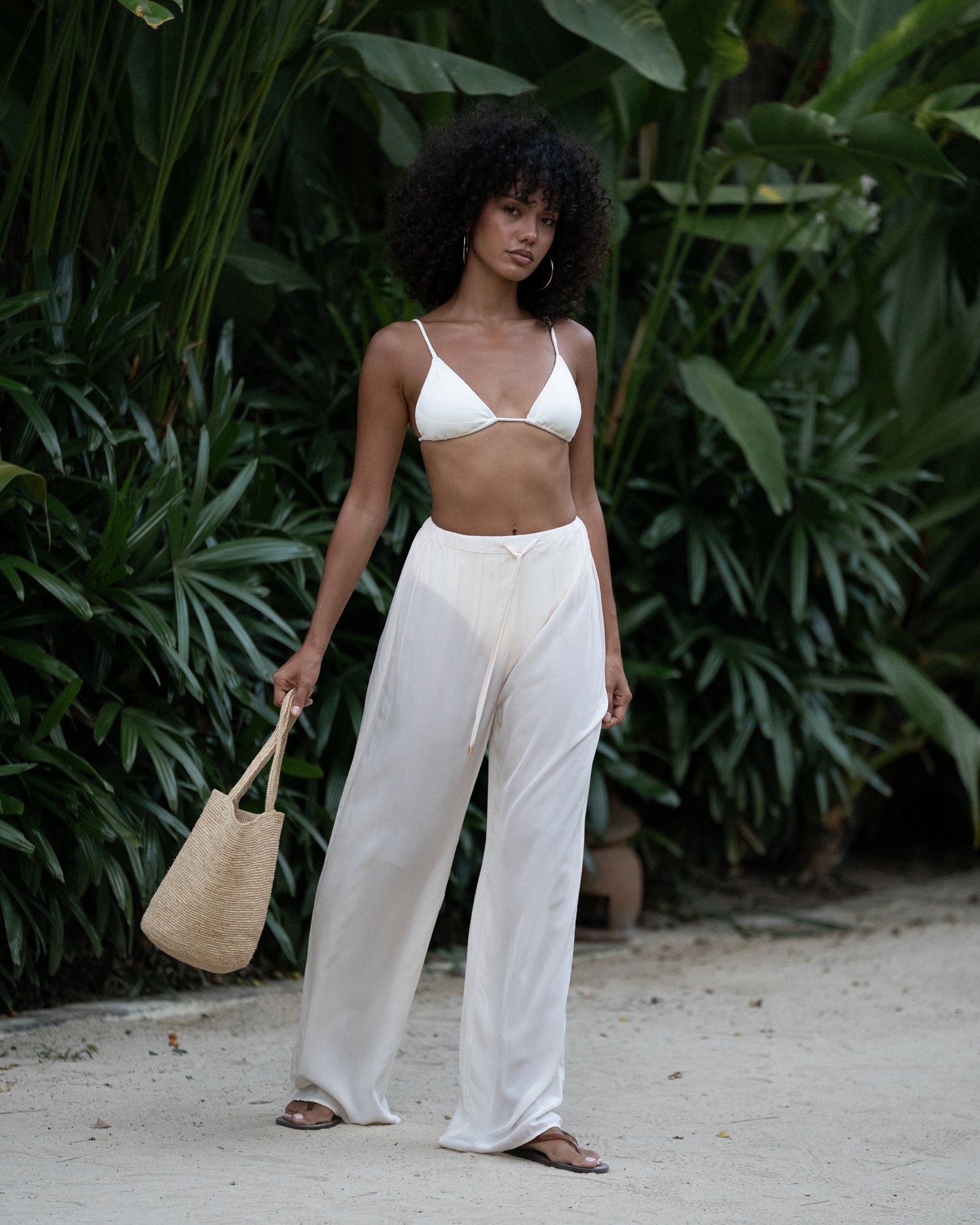 Ivory viscose drawstring beach pants styled with a white triangle bikini top and straw bag — honeymoon resort wear