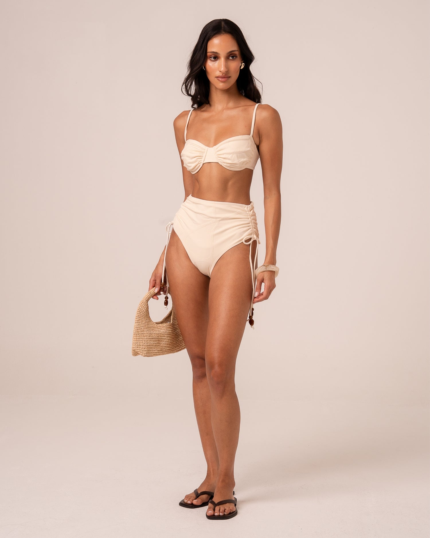 Model wearing an ivory soft cup bralette bikini top with ruched centre gathering, styled with a high waist bottom — studio front view