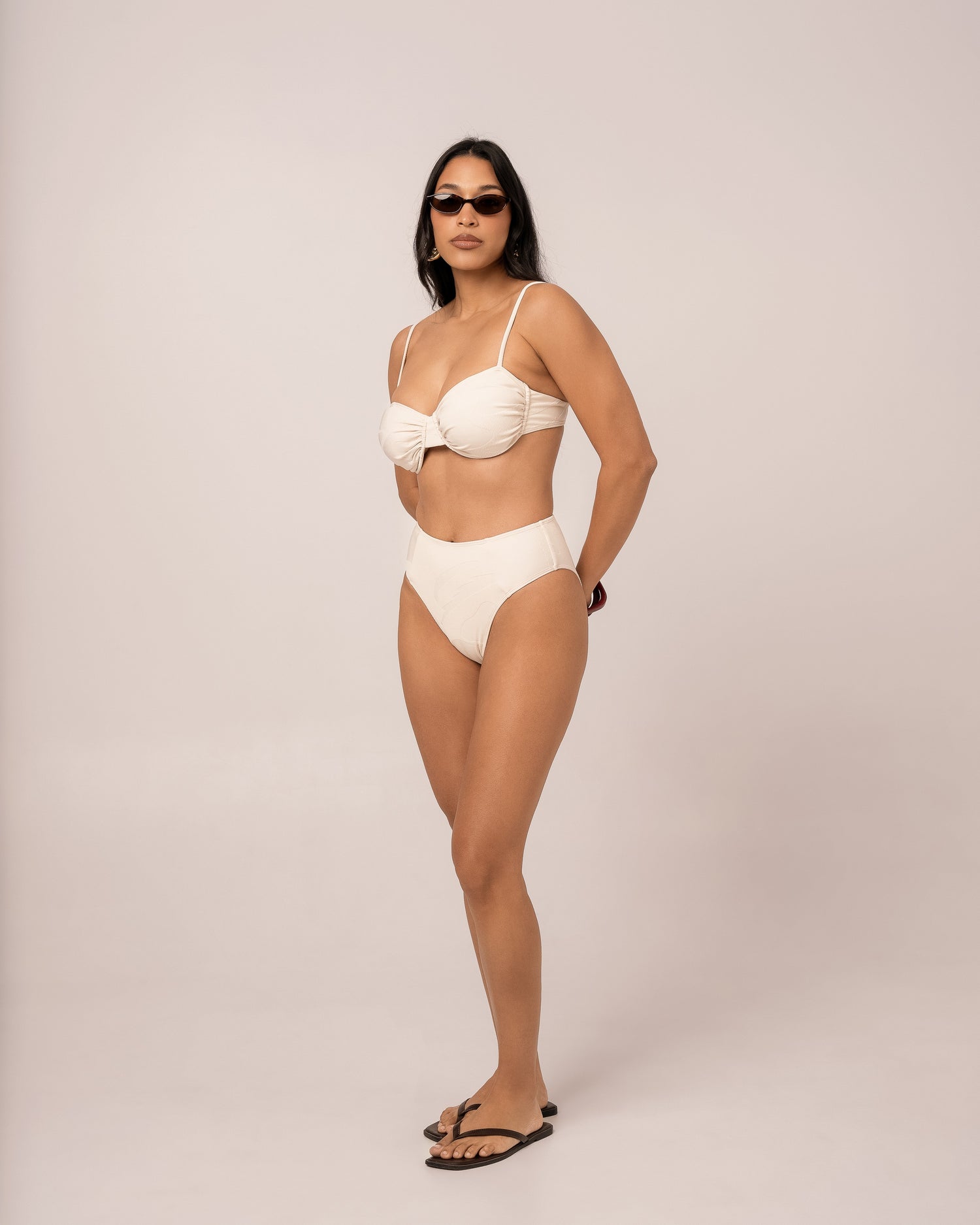 Ivory mid rise bikini bottom with spliced panel seams and a higher-cut leg, styled with a soft cup bralette — size 12 studio front view