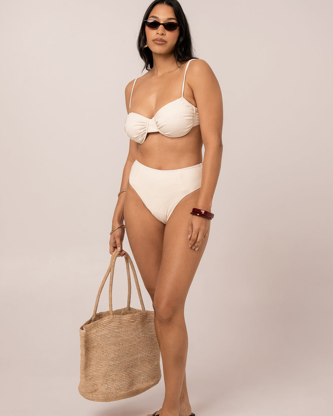 Ivory mid rise bikini bottom shown at the hip, the elongating spliced seams and higher leg foregrounded on a size 12 fit — studio side view