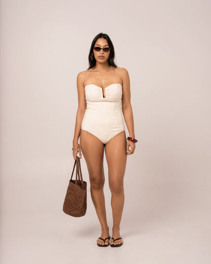 Model wearing an ivory strapless bandeau one piece swimsuit with a V-wire plunge neckline, studio front view