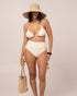 Model wears the ivory string triangle bikini top with thin adjustable straps and jacquard rib texture, front studio view.