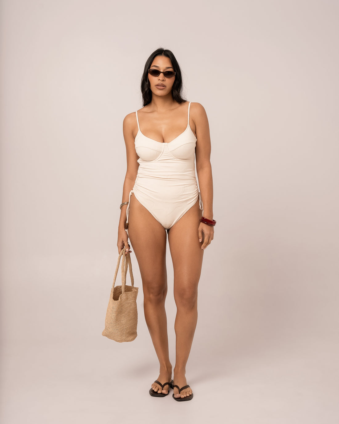 Model wearing an ivory thin strap underwire one piece swimsuit with structured cups, studio front view
