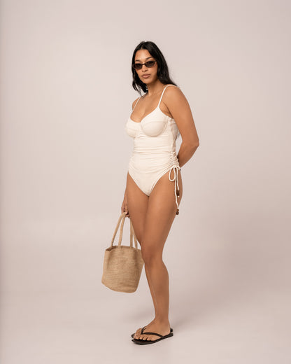 Ivory thin strap underwire one piece swimsuit with ruched adjustable side ties, studio three-quarter view