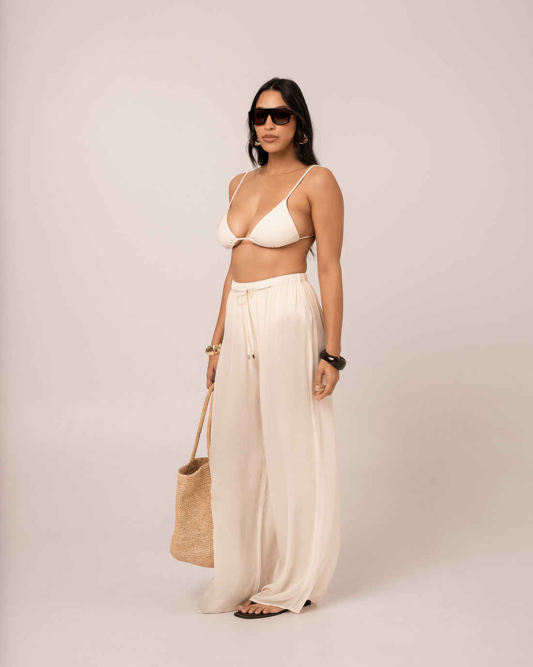 Side view of the ivory wide-leg resort pant showing its long column-like flowing leg line